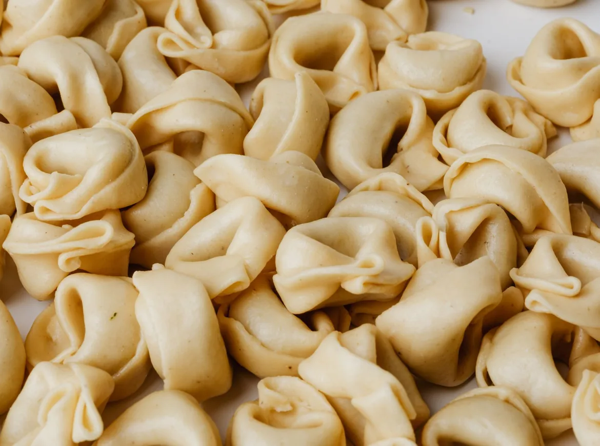 A heap of freshly made tortellini on a pale surface